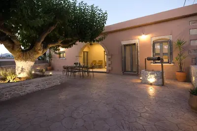 a patio with a tree and chairs and a building at Villa Savina in Plátanos
