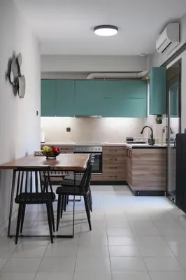 a kitchen with green cabinets and a wooden table and chairs at Dedalos City Apartment in Chania Town