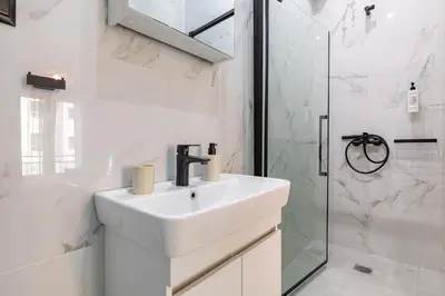 a white bathroom with a sink and a shower at Jo's Central & Cozy Apartment in Chania Town