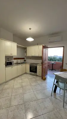 a large kitchen with white cabinets and a table at Murele apartments in Daratso