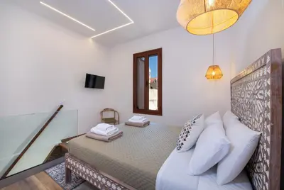 a bedroom with a bed with white pillows and a mirror at Casa Dione - Chania Old Town in Chania Town