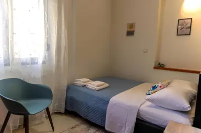 a small bedroom with a bed and a chair at Laurels Apartment in Chania Town