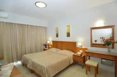 a bedroom with a bed and a desk and a mirror at Nektar Beach Hotel in Stalos