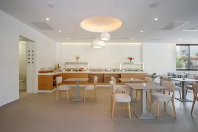 a dining room with tables and chairs and a kitchen at Phos Hotel Adults Only in Plataniás