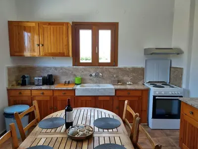 a kitchen with a table with a bottle of wine at All Season Lovely Seafront Cottage in Kissamos