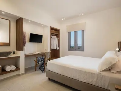 a white bedroom with a bed and a desk at Villa Seyian in Chania Town