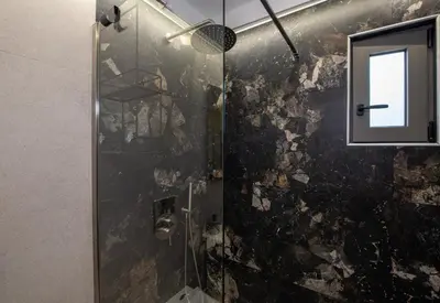 a bathroom with a glass shower with a window at Kalopsia Luxury Apartment Near Chania in Chania Town