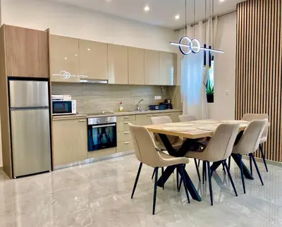 a kitchen with a table and chairs and a refrigerator at Stone Luxury Suite in Galatás