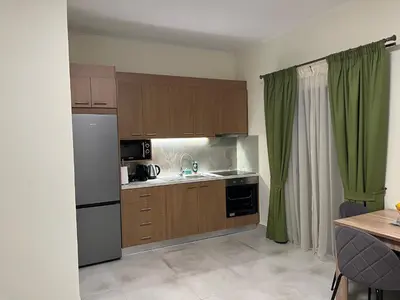 a kitchen with wooden cabinets and a white refrigerator at GREENHOUSE maleme in Ayiá