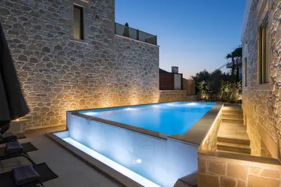 a swimming pool in a backyard with a brick wall at Luxury villas Argalios in Drapaniás