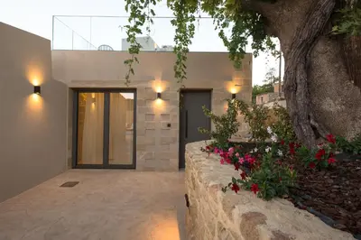 a house with a stone retaining wall with flowers at Basiliko in Kalidhónia
