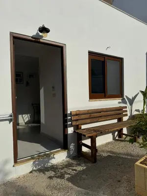 a wooden bench sitting outside of a building with a mirror at Kasteli Apartment in Kissamos
