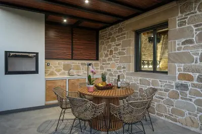 a stone kitchen with a wooden table and chairs at Semes luxury villas in Drapaniás