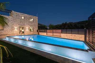 a swimming pool with lights in a backyard at night at Semes luxury villas in Drapaniás
