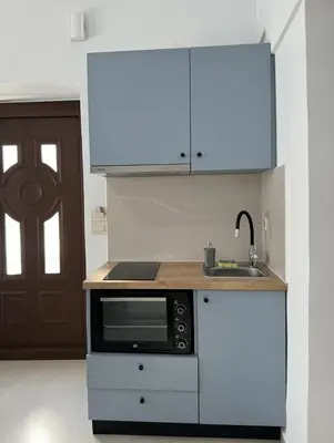 a white kitchen with a microwave and a sink at Kasteli loft apartment in Kissamos