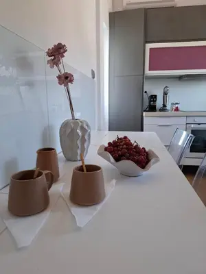 a white table with a vase of flowers and a bowl of fruit at UPapartment in Chania Town