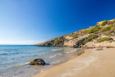 a beach with a rock in the sand and the ocean at PhySea Villa in Kalathas
