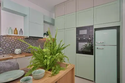 a kitchen with white cabinets and a table with plants at Mantis' House in Chania Town