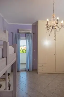 a bedroom with purple walls and a chandelier at Kaloudis Apartment in Kissamos