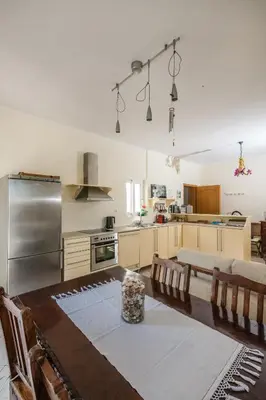 a kitchen with a table and a stainless steel refrigerator at Kaloudis Apartment in Kissamos