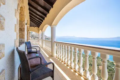 a balcony with two chairs and a view of the ocean at Villa Sun Rock - Ravdoucha in Kolymvari
