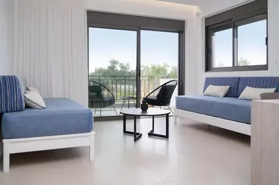 a living room with a blue couch and a table at Niki Luxury Suites Pool Resort 200m From Beach in Chorafakia