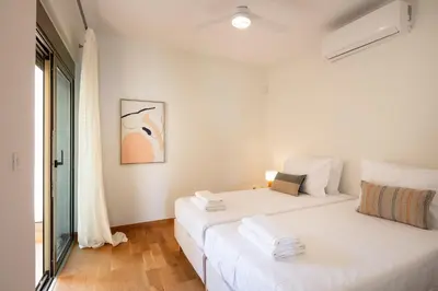 a white bedroom with two beds and a window at Kalyves Coastal Retreat in Chania Town