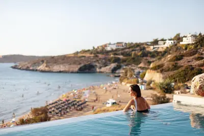 a woman sitting in a swimming pool next to a beach at Beach Rock in Chania Town