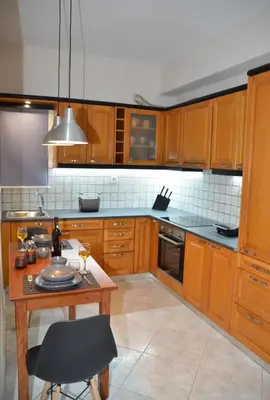 a kitchen with wooden cabinets and a table with a chair at Vaso's comfort apartment 1 in Chania Town