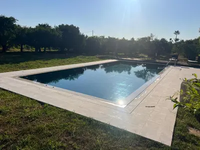 a large swimming pool in a field with a grass field at Tzortzinas Cottage in Chania Town