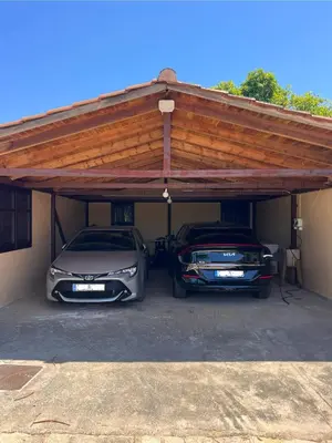 two cars parked in a garage with a wooden roof at Tzortzinas Cottage in Chania Town