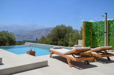 a villa with a swimming pool and two lounge chairs at Serenity in Stérnai