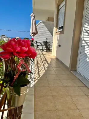 a balcony with red flowers and an umbrella at Dream Apartments 3 in Palaiochóra
