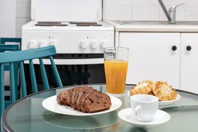 a glass table with a plate of cake and a glass of orange juice at Koum Kapi Mare Studios C2 in Chania Town