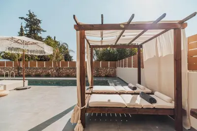 a canopy bed on a patio next to a pool at Nos Aqua Villas Chania in Pazinos