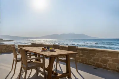 a wooden table and chairs on a balcony overlooking the ocean at Villa Maistros in Kissamos