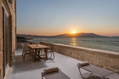 a table and chairs on a balcony with the sunset at Villa Maistros in Kissamos