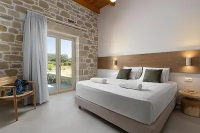 a bedroom with a large bed and a stone wall at Villa Maistros in Kissamos