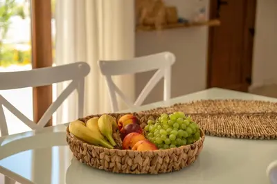a basket of fruit on a table with two chairs at Superior Argilos Cottage Private Pool - 300m From the beach in Korfalónas