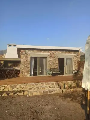 a stone house with a wooden porch and windows at Mekia's beach house in Livadia