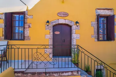 a yellow house with a brown door and a balcony at SternesVillage, Premium Balcony Suite in Stérnai
