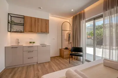 a bedroom with a bed and a kitchen with a window at Kiwi Boutique Studios in Kissamos