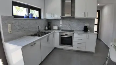 a kitchen with white cabinets and a sink and a window at Stefanie's House in Chania Town