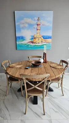 a wooden table with chairs and a painting of a lighthouse at Fiorella Sea View Pool Villa in Kalyves, Chania area, Crete in Kalyves