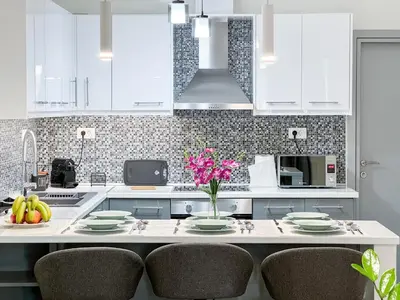 a kitchen with white cabinets and a table with chairs at All Seasons Luxury Apartment in Chania Town