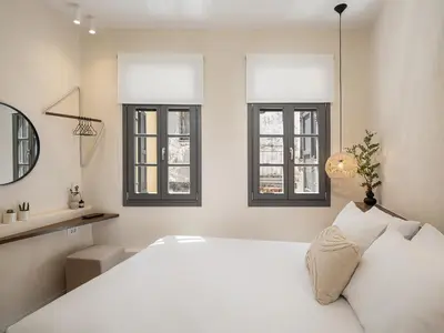a bedroom with a white bed and two windows at Green Lilly Home in Chania Town