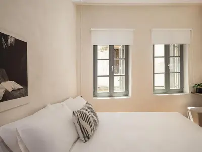 a white bed in a room with two windows at Green Lilly Home in Chania Town