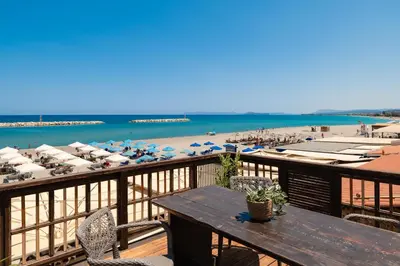 a balcony with a table and a beach with umbrellas at Ekati Seaside Living in Kolymvari