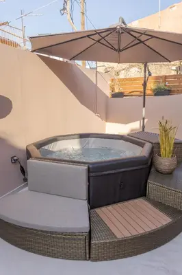 a hot tub sitting on a patio with an umbrella at Comfinest in Chania Town