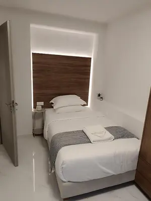 a bedroom with a large bed with a wooden headboard at The Athena Apartment, Chania Seaside in Chania Town
